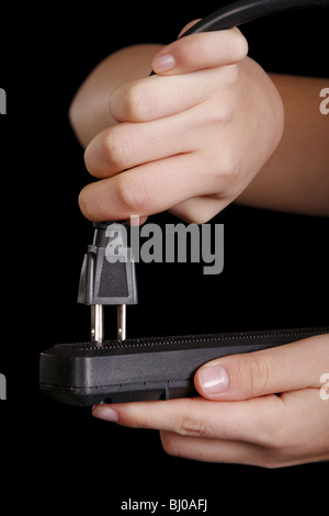 Mani collegando un cavo elettrico in una striscia di alimentazione Foto Stock