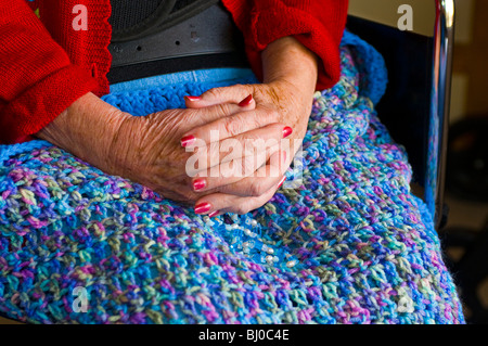 Invecchiamento Womans mani appoggiate sulla coperta di maglia. Foto Stock