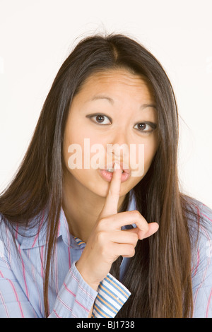 Donna asiatica con un dito nella parte anteriore delle labbra Foto Stock