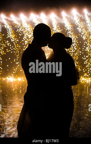 Silhouette della sposa e lo sposo baciare in fronte di fuochi d'artificio Foto Stock