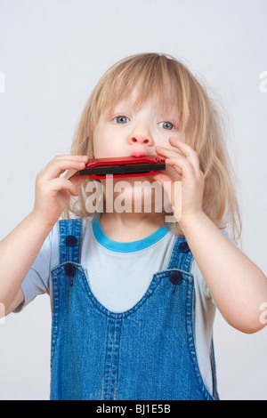 Ragazzo con capelli lunghi biondi riproduzione armonica Foto Stock