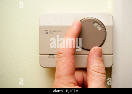 Un modello rilasciato foto di qualcuno ruotando il termostato riscaldamento fino nel Regno Unito Foto Stock