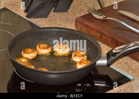 Funghi essendo saltate in una padella con il burro con pepe macinato sul momento Foto Stock