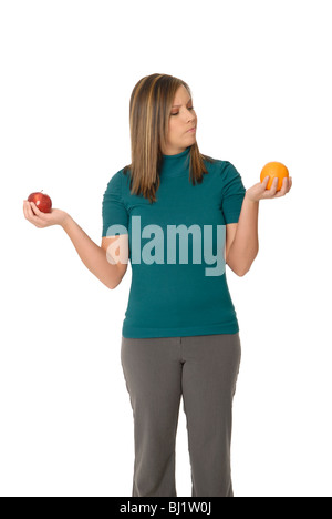 Una giovane donna di un confronto tra un Apple e un'arancia: 'confrontando le mele alle arance'. Foto Stock