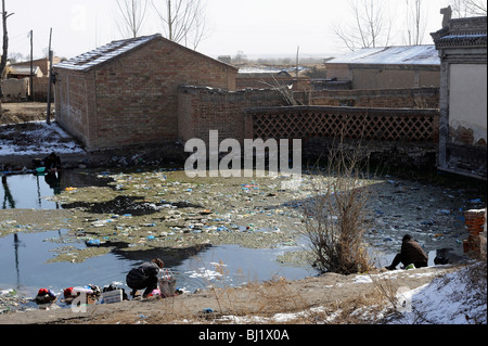 Le donne a lavare i panni in un stagno inquinato in un paesino della provincia di Hebei, Cina. 02-Mar-2010 Foto Stock