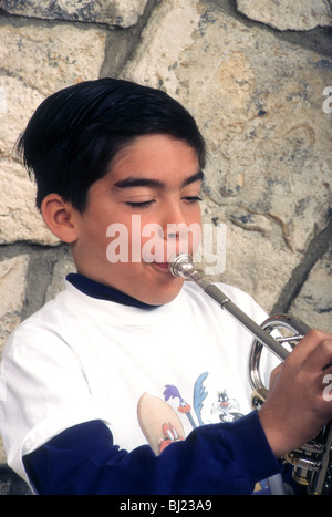 Ispanico ragazzo di nove anni suona la tromba strumento musicale colpo creare suoni di boccaglio in ottone Foto Stock