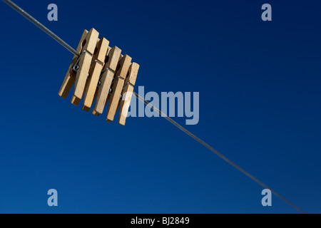 Cinque clothespegs close up appeso su una linea di lavaggio con cielo blu Foto Stock