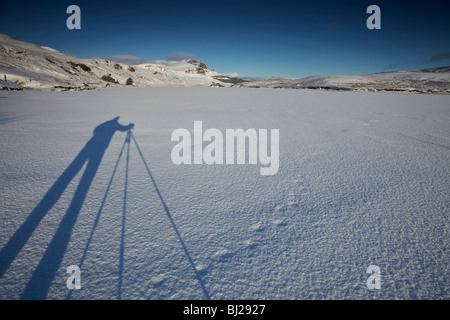 Fotografo ombra sulla neve, Loch fada, Storr, Isola di Skye in Scozia Foto Stock