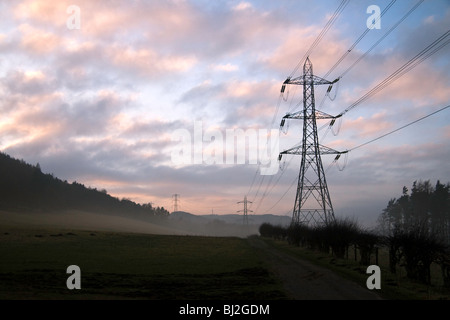 Un tramonto in una nebbiosa, giornata invernale e al Pentland Hills. Tralicci di energia elettrica si dipanano attraverso il paesaggio nella distanza Foto Stock