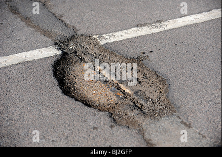 Una profonda buca nella strada causate dal recente la neve e il gelo Foto Stock