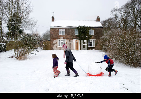 Tre bambini tirando una slitta passato una casa con una faccina sorridente in un villaggio in East Yorkshire. Foto Stock