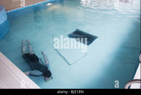 Uomo di effettuare interventi di manutenzione sul sistema idraulico su un celato piscina con un pavimento submergeable. Foto Stock