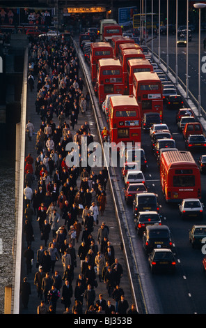 Migliaia di ora di punta pendolari pour verso nord oltre il Ponte di Londra contro la direzione di queueing autobus e automobili. Foto Stock