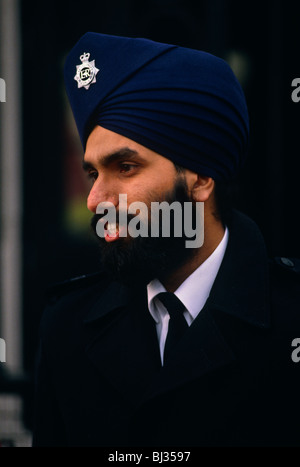 La Metropolitan police officer della fede sikh si erge fuori Buckingham Palace indossando un badge incontrato sul suo turbante. Foto Stock