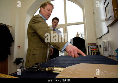 Maestro sarto Thomas Mahon istruire il suo nuovo apprendista nel commercio di sartoria presso la sua base di Carlisle Warwick Hall, Cumbra Regno Unito Foto Stock