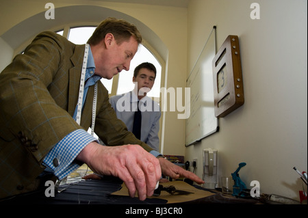 Maestro sarto Thomas Mahon istruire il suo nuovo apprendista nel commercio di sartoria presso la sua base di Carlisle Warwick Hall, Cumbra Regno Unito Foto Stock