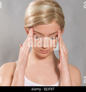 Giovane donna sta toccando i suoi templi Foto Stock