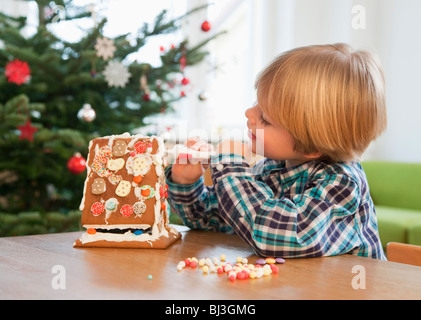 Ragazzo decorare gingerbread house Foto Stock