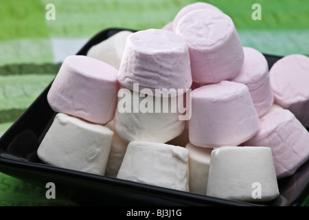 Pila di colore rosa e bianco marshmallows su una piastra nera Foto Stock