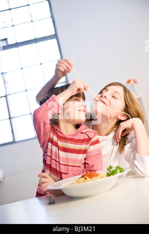 Due ragazze mangiare spaghetti insieme Foto Stock