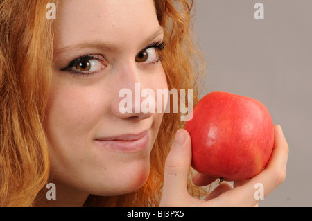 Volto di una donna redhaired tenendo una mela rossa Foto Stock