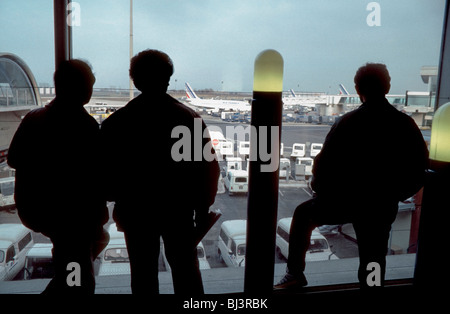 Parigi, Francia, Aeroporto Roissy-Charles-de-Gaulle Roissy, Silhouette, passeggeri maschi in attesa del loro volo. Guardando fuori dalla finestra, il gruppo si alza da dietro Foto Stock