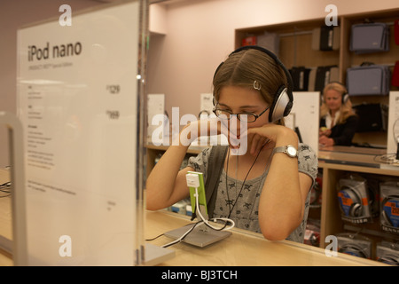Dodici anni di-vecchia ragazza visitando la filiale di Londra di un Apple Store a Londra in Regent Street, ascolta un iPod nano. Foto Stock