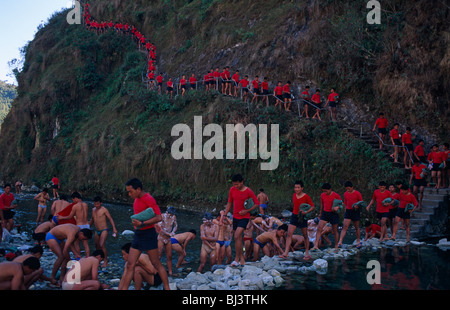 Fiume regolare lavaggio identici per giovani ragazzi nepalesi camminando in single-file giù valle laterale al Gurkha training camp. Foto Stock