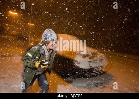 Un bambino gioca snowballs di notte durante una forte bufera di neve nel centro di Londra - un evento raro per un interno della città. Foto Stock