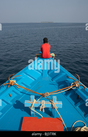 Un crewman maldiviano utilizza un telefono cellulare dopo una giornata di pesca al tonno a bordo di un dhoni barca da pesca in una zona remota dell Oceano Indiano Foto Stock