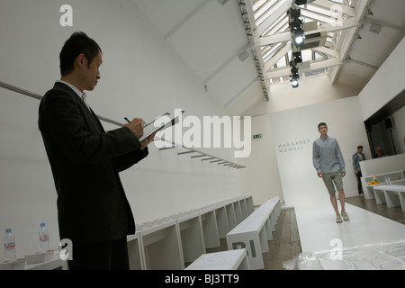 Modello di ragazza che ripete ai team di progettazione prima di British designer di moda Margaret Howell in autunno fashion show in design studio Foto Stock