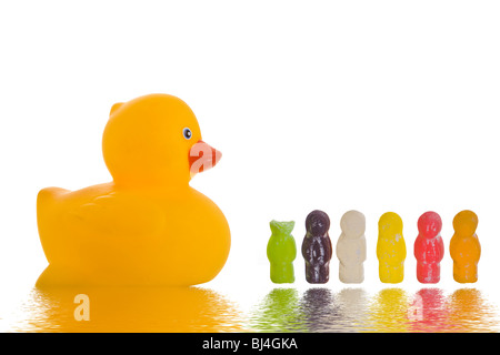 Conceptual Jelly baby shot con un anatra di gomma di mangiare il modo attraverso una fila di candy Foto Stock