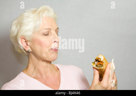 Una donna - eyeing una salsiccia in una baguette con sospetto Foto Stock