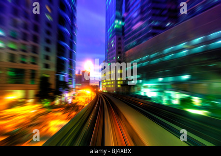 Treno ad alta velocità che passa tra Kuala Lumpur City durante il crepuscolo ora. Focus sul rail road. Foto Stock