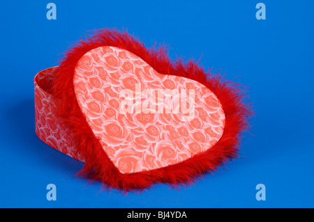 Bella rossa a forma di cuore scatola Fancy silhouette isolato su sfondo blu. Il giorno di San Valentino idea regalo Foto Stock