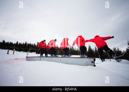 Uomo snowboard, la sequenza di molti colpi. Un uomo che indossa una giacca rossa è lo snowboard su una rampa. Overcast. Foto Stock