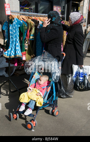 Regno Unito musulmani e le donne indiane con il bambino nel passeggino shopping al mercato di Whitechapel nella zona est di Londra Foto Stock