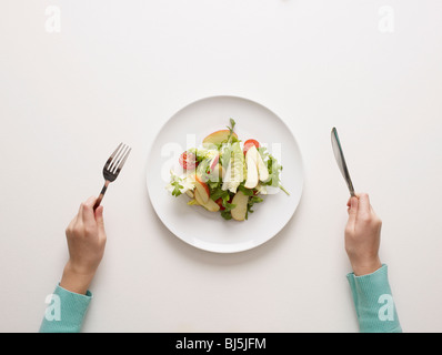 Le mani da un piatto di insalata Foto Stock