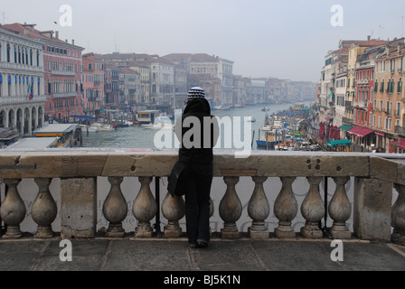 Una ragazza solitaria sorge sul ponte di Rialto, affacciato sul Grand Canal, Venezia Italia. Foto Stock