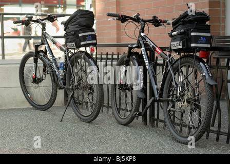 Due forze di polizia di Vancouver biciclette sul suo stand bike, fino contro una ringhiera. Foto Stock
