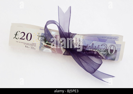 Arrotolato su vecchia sterlina 20 £libbra nota GBP legato con un nastro viola su uno sfondo bianco normale. Dare il concetto di regalo di denaro. Inghilterra Regno Unito Gran Bretagna Foto Stock
