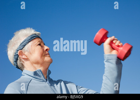 Attiva donna senior titolare di pensione o di rendita facendo un allenamento che indossa una Fascia assorbisudore pur esercitando con pesi pesi a mano per mantenere sani. Regno Unito Gran Bretagna Foto Stock