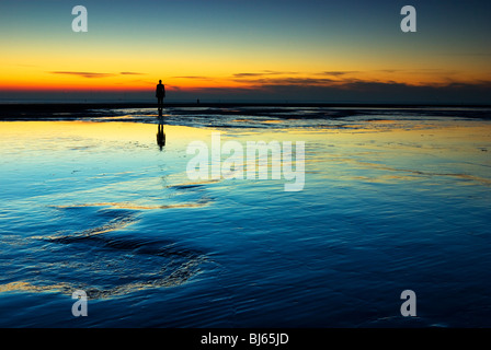 Colouful tramonto a Crosby beach, con uno di Anthony Gormly statue Foto Stock