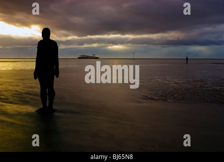 Colouful tramonto a Crosby beach, con uno di Anthony Gormly statue Foto Stock