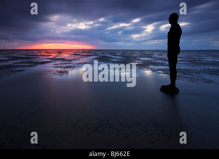 Colouful tramonto a Crosby beach, con uno di Anthony Gormly statue Foto Stock