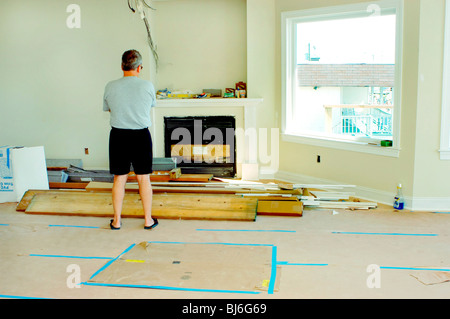 Proprietario maschio del Condominio, uomo in piedi dentro da dietro, guardando i lavori di costruzione in corso nel salotto di casa. "Ocean City", New Jersey, Stati Uniti, soggiorno di classe media con interni Foto Stock