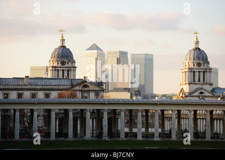 Le torri della Old Royal Naval College di Greenwich, Londra, Regno Unito, un sito del patrimonio mondiale, con Canary Wharf in background al crepuscolo Foto Stock