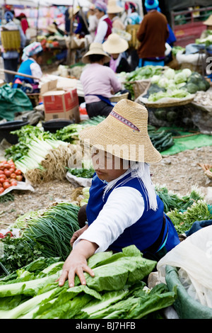 Donna vendita di verdure al mercato settimanale di formatura (vicino a Dali), nella provincia dello Yunnan in Cina. Foto Stock