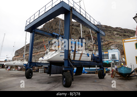 Yacht sollevato al di fuori dell'oceano da un paranco mobile nella marina di Puerto de Mogan gran canaria Foto Stock