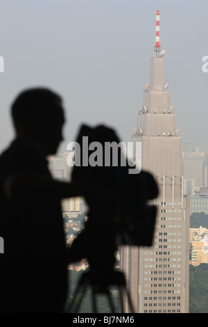 Cameraman tv in silhouette riprese NTT DoCoMo edificio, in Shinjuku, Tokyo, Giappone, Agosto 6th, 2007.